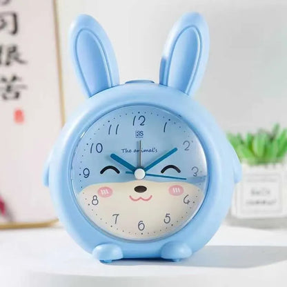 Cartoon-style children's alarm clock in pink or blue, showing buttons for night light and alarm functions.