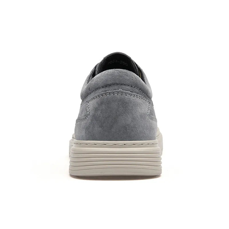 Men's grey low-top casual leather skate shoes with round toe and flat rubber sole on a wooden surface.