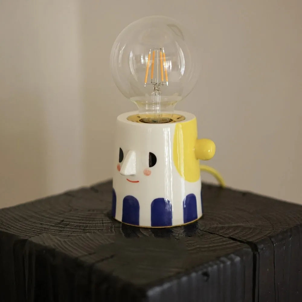 Handmade ceramic lamp with ball headlight design on a bedside table