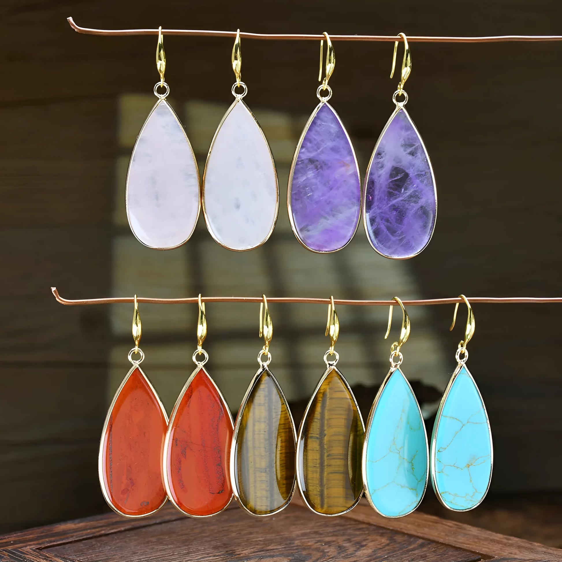 Close-up of long, polished tigereye stone drop earrings with a fishhook clasp on a neutral background.