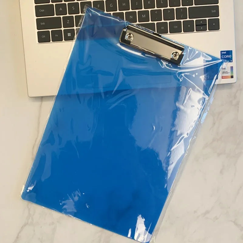 Transparent A4 writing board pad with metal flat clip in blue, alongside A5 size in red on a desk.