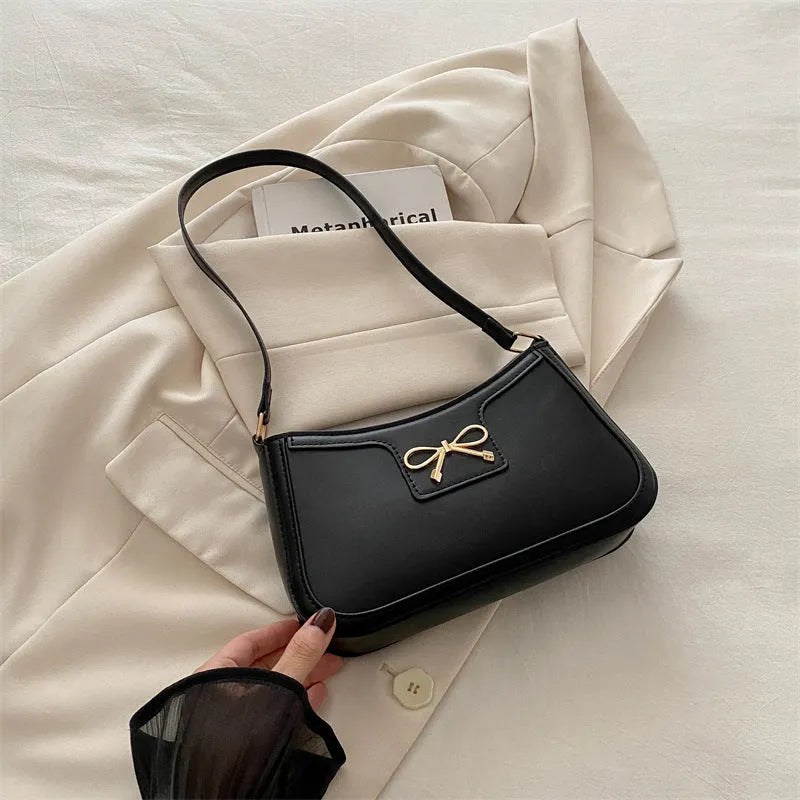 Western style shoulder bag with bow detail in rose pink colour, showing horizontal square shape and single strap.