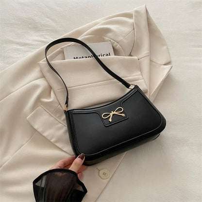 Western style shoulder bag with bow detail in rose pink colour, showing horizontal square shape and single strap.