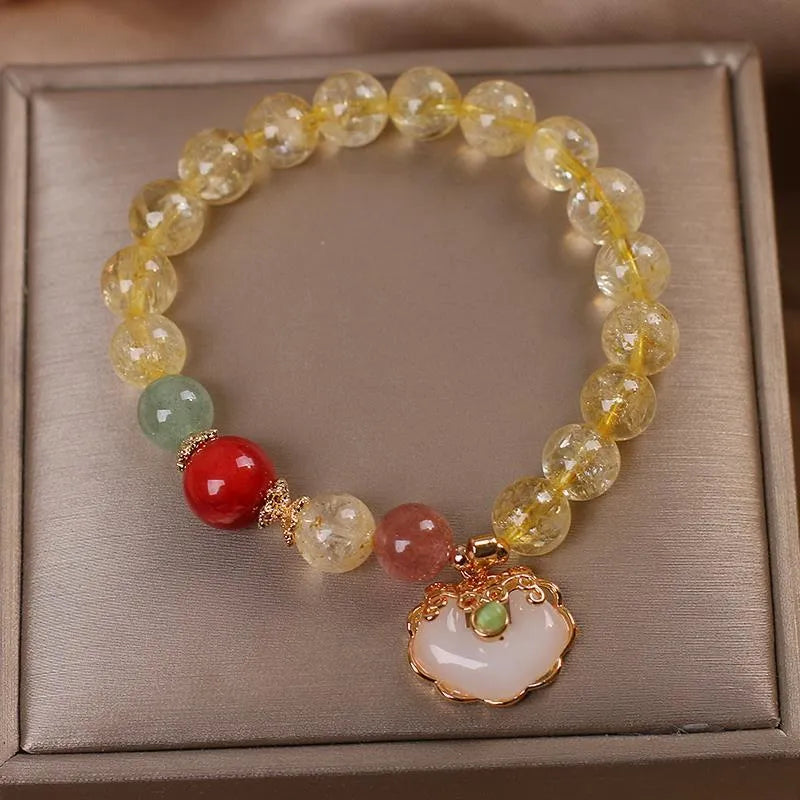 Women's yellow citrine jade ruyi pendant bracelet on wrist, alloy construction.