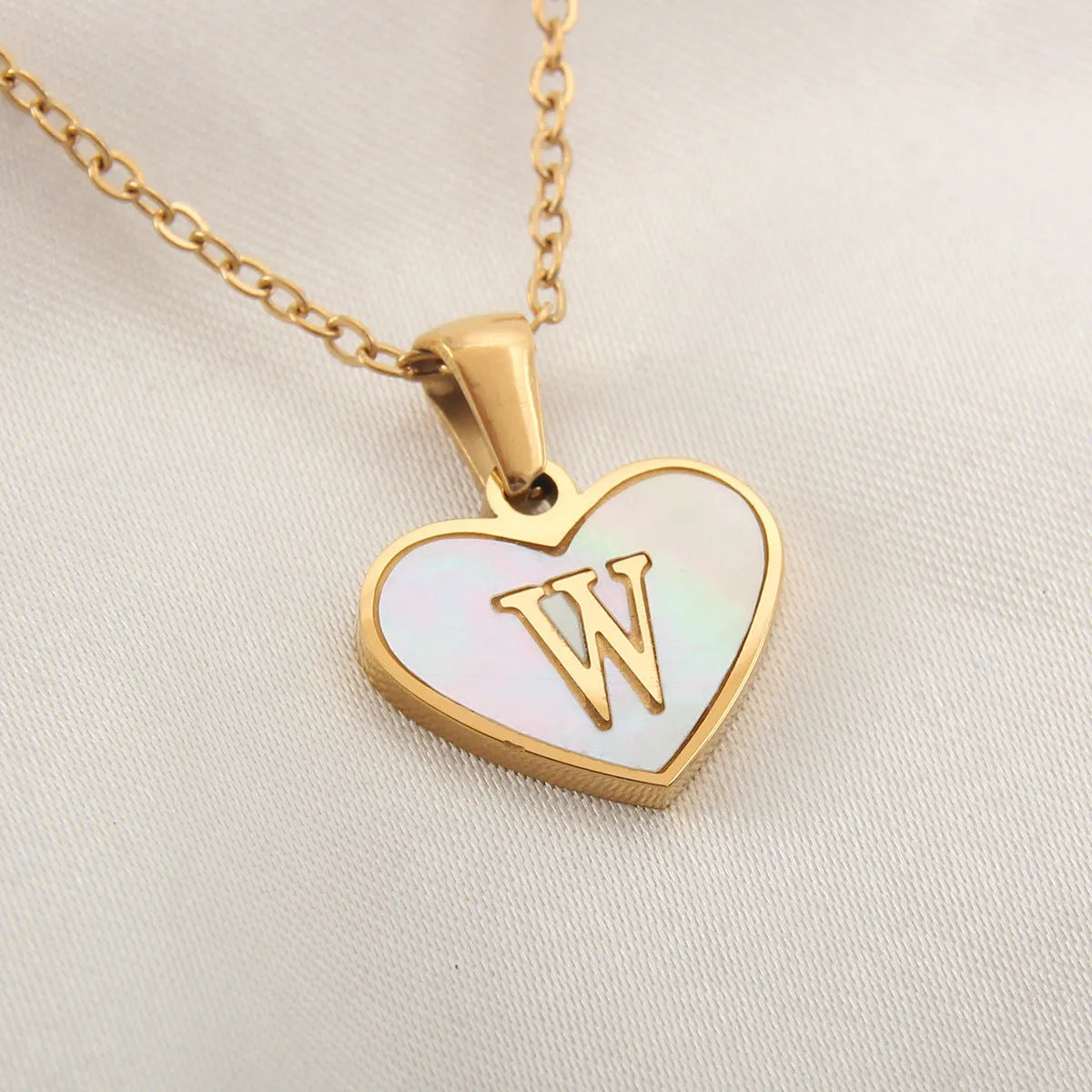 Gold-plated clavicle necklace with a white shell heart pendant, personalised with a letter from A to Z.