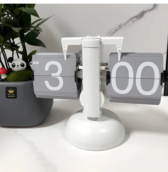 Black and white flip digital clock showing 12:34 with retro flip digits on wooden table