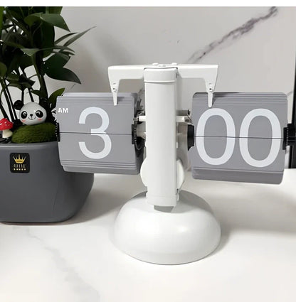 Black and white flip digital clock showing 12:34 with retro flip digits on wooden table