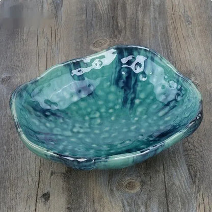 Japanese style irregular shaped ceramic sashimi bowl with floral decoration on table.
