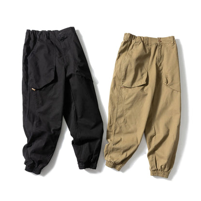 Black cotton casual pants with large pockets, tapered legs, and ankle ties on a hanger.