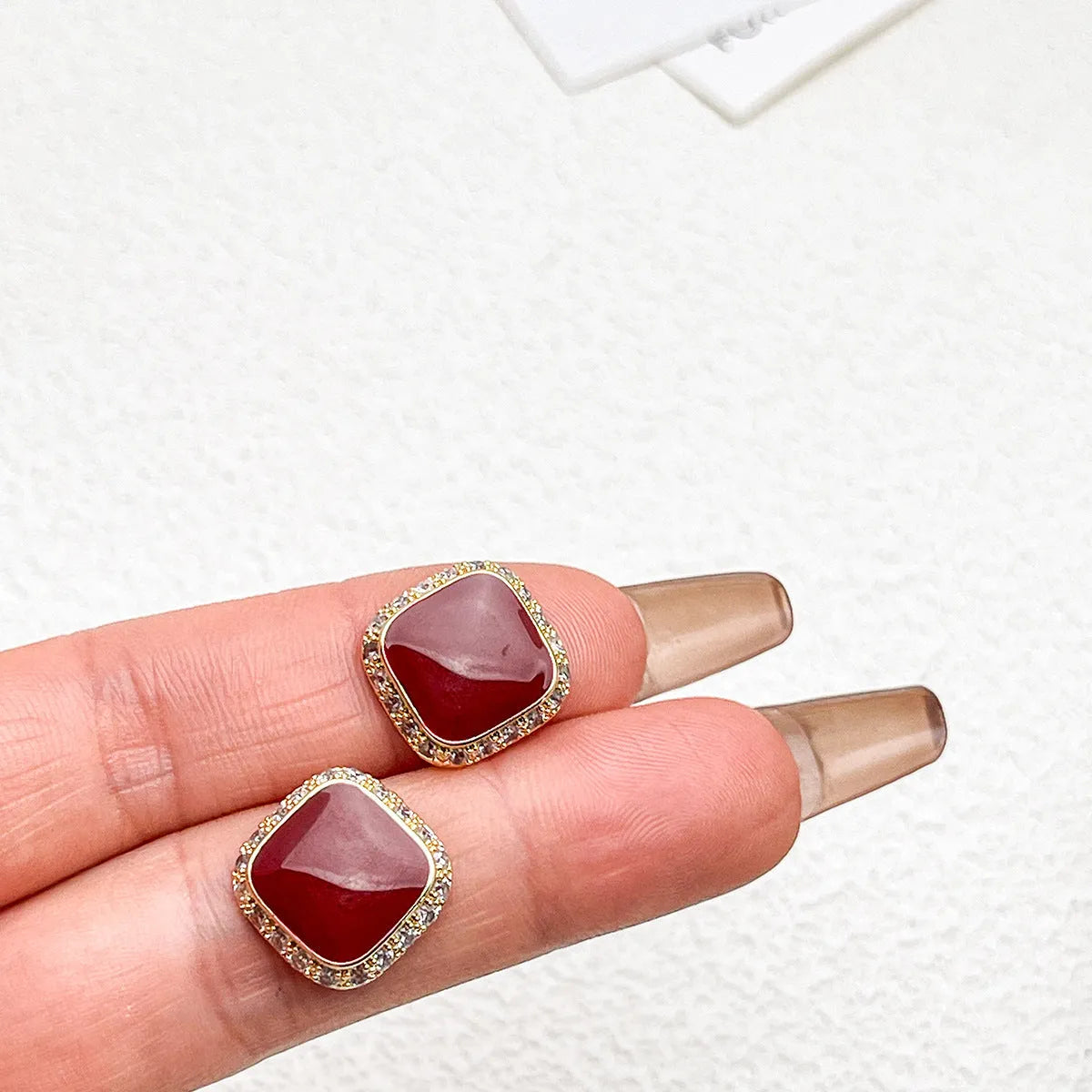 Red square alloy earrings with an inlaid geometric design, shown from the front.
