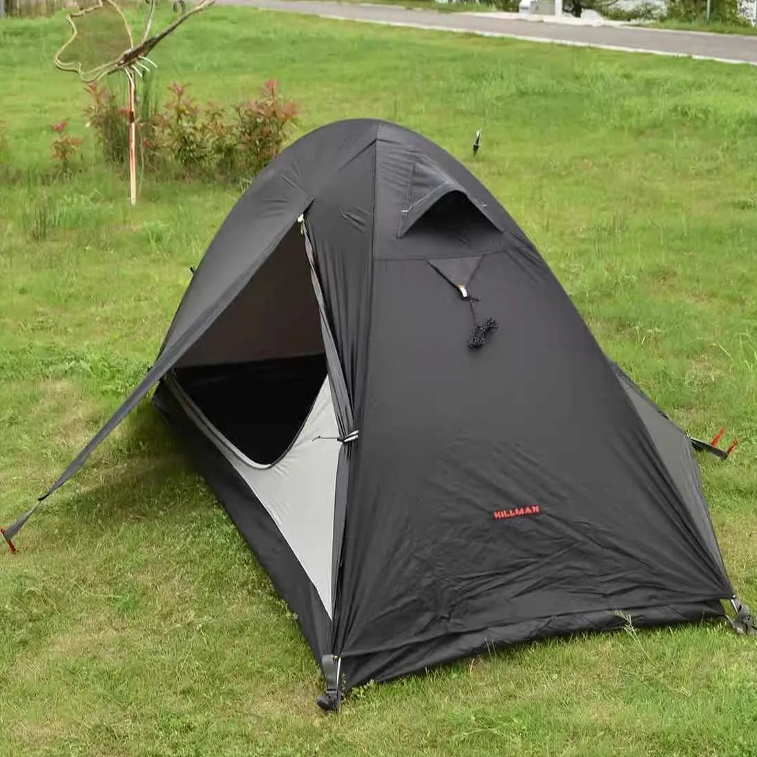 Single person tent with aluminium poles, silicon coating, and double-layer design in black colour, set up outdoors