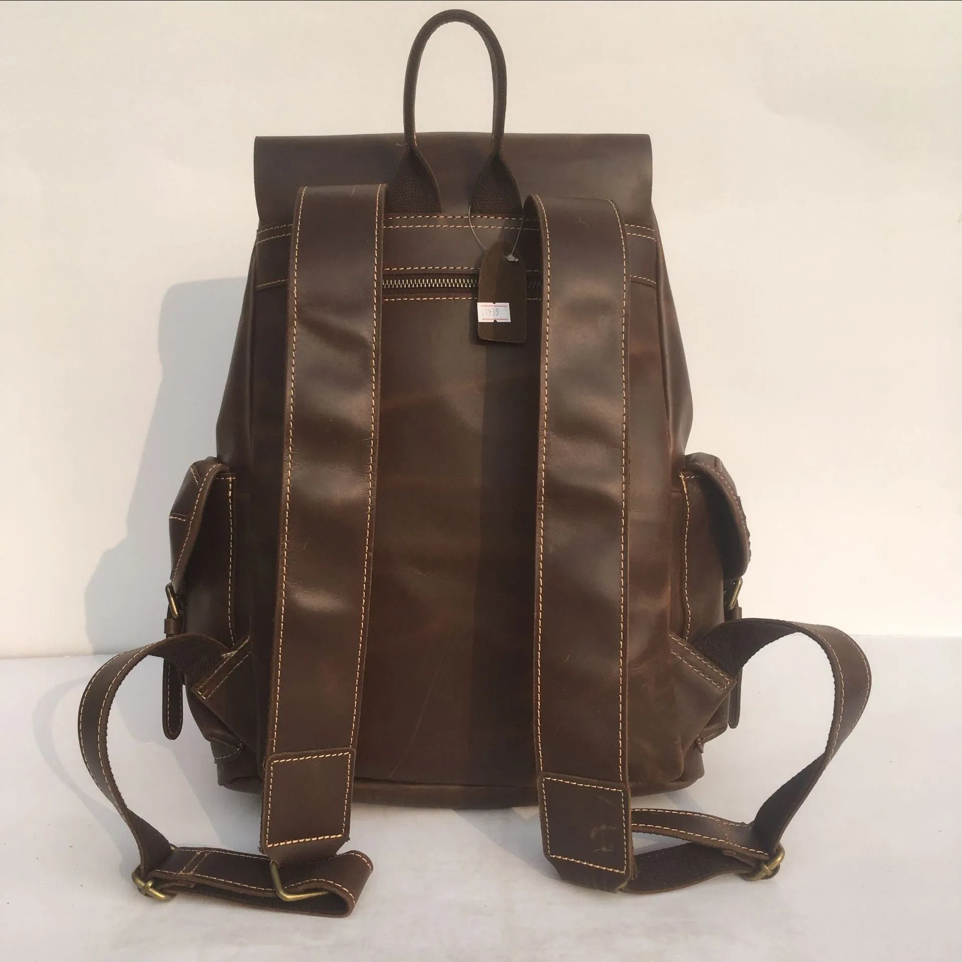 Men's brown leather backpack showing cowhide texture and air pillow belt system