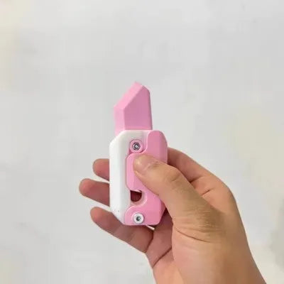 Small orange and green 3D printed plastic carrot knife fidget toy with blade extended.