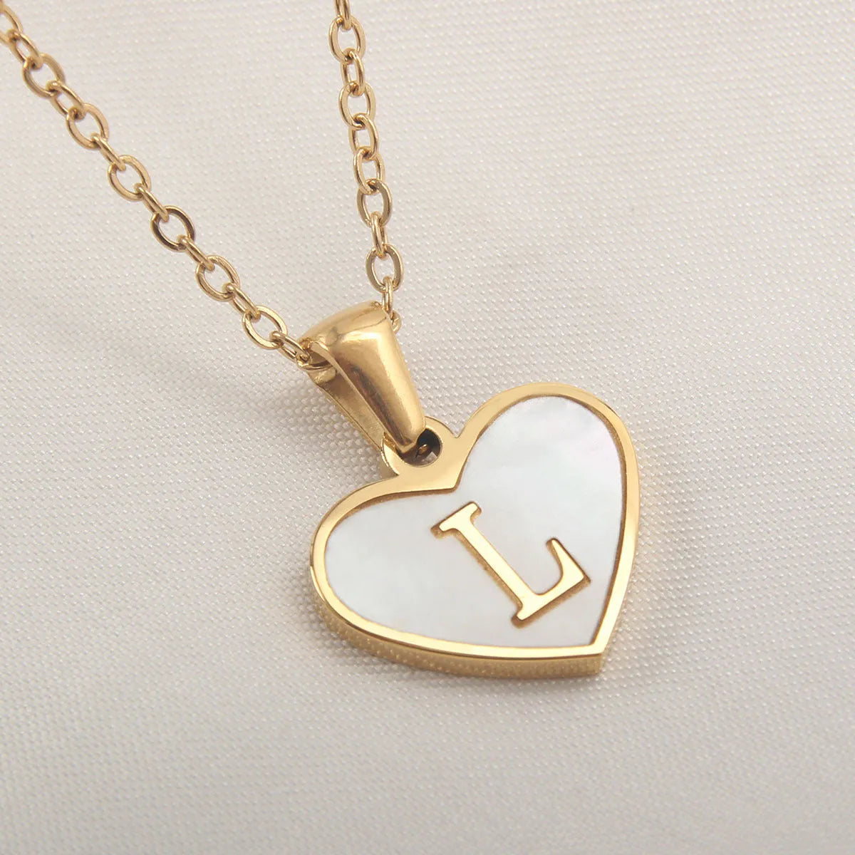 Gold-plated clavicle necklace with a white shell heart pendant, personalised with a letter from A to Z.
