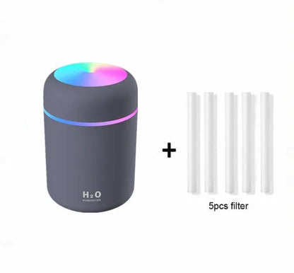 Pink car air purifying humidifier with LED lights on, next to a USB cable.