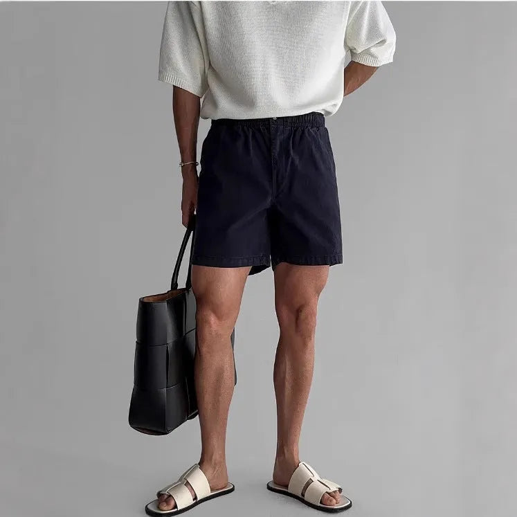 Men's loose-fit cotton sports shorts in black, shown on a hanger