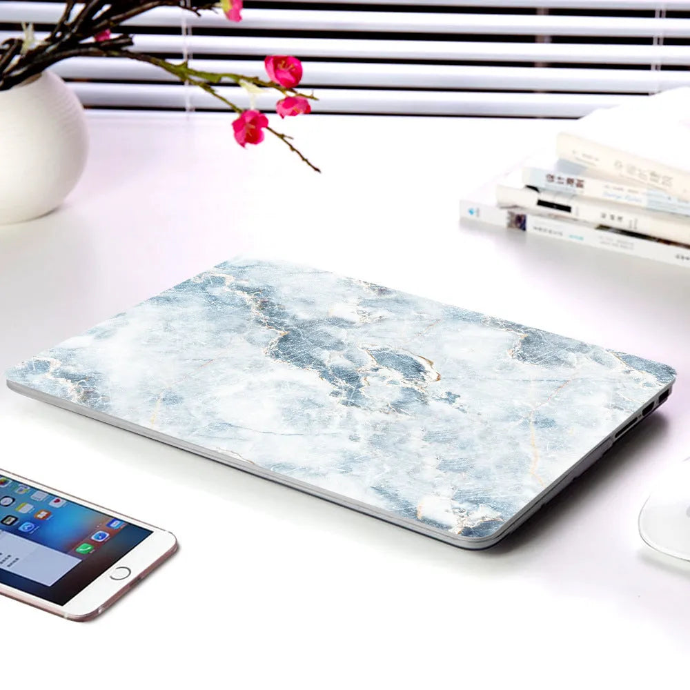 Plastic MacBook protective case in a marble pattern colour, shown next to a compatible Apple laptop.