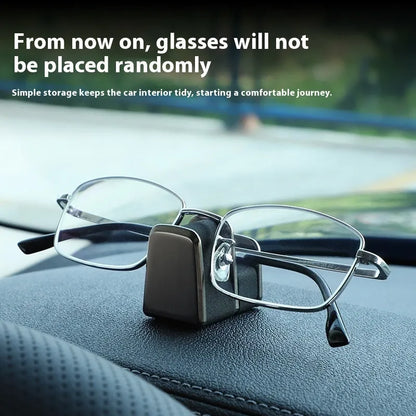 Green zinc alloy and leather glasses clip holder attached to a car dashboard, holding sunglasses.
