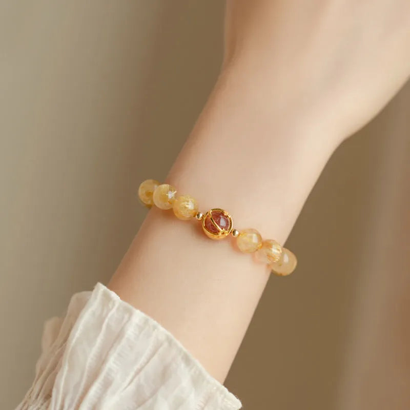 Citrine and gold rutilated quartz stretch bracelet with diamond-cut beads on an elastic band.