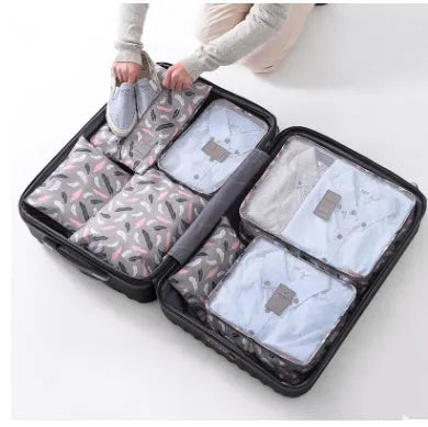 Set of six coloured nylon packing cubes and flat pouches for travel organisation.