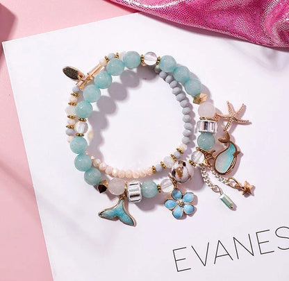 Elegant whale tail bracelet in vibrant colors with flower and starfish accents, perfect for adding a touch of coastal charm to any outfit.