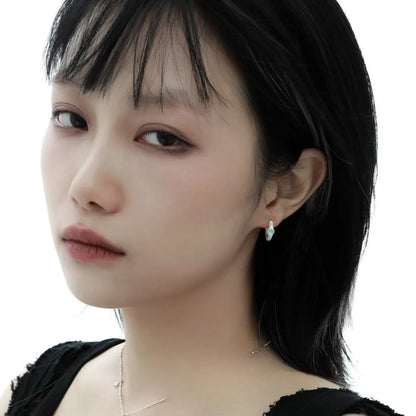 A pair of geometric round ear clips made from 925 silver with a burnt silver electroplated finish.