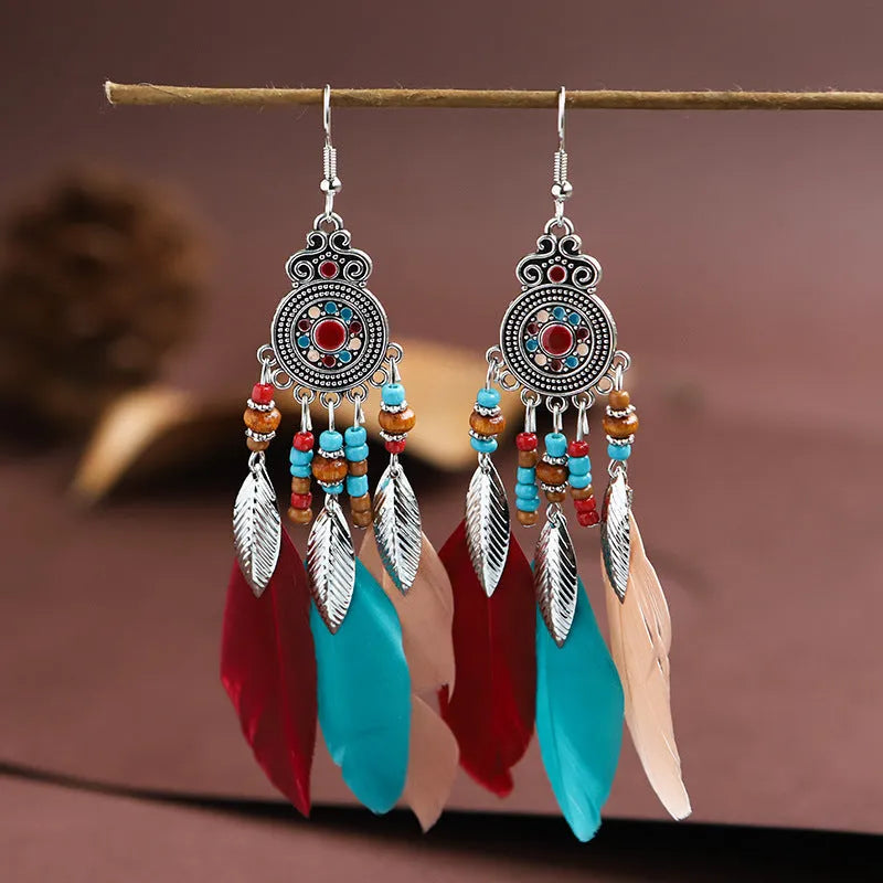 Bohemian feather leaf pattern alloy earrings in round drop shape on a colour selection background.