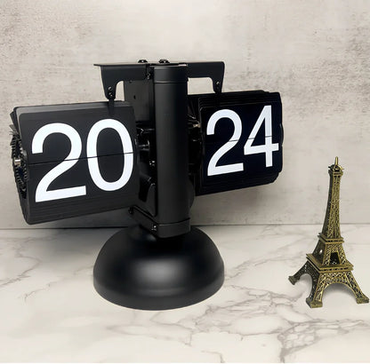 Black and white flip digital clock showing 12:34 with retro flip digits on wooden table