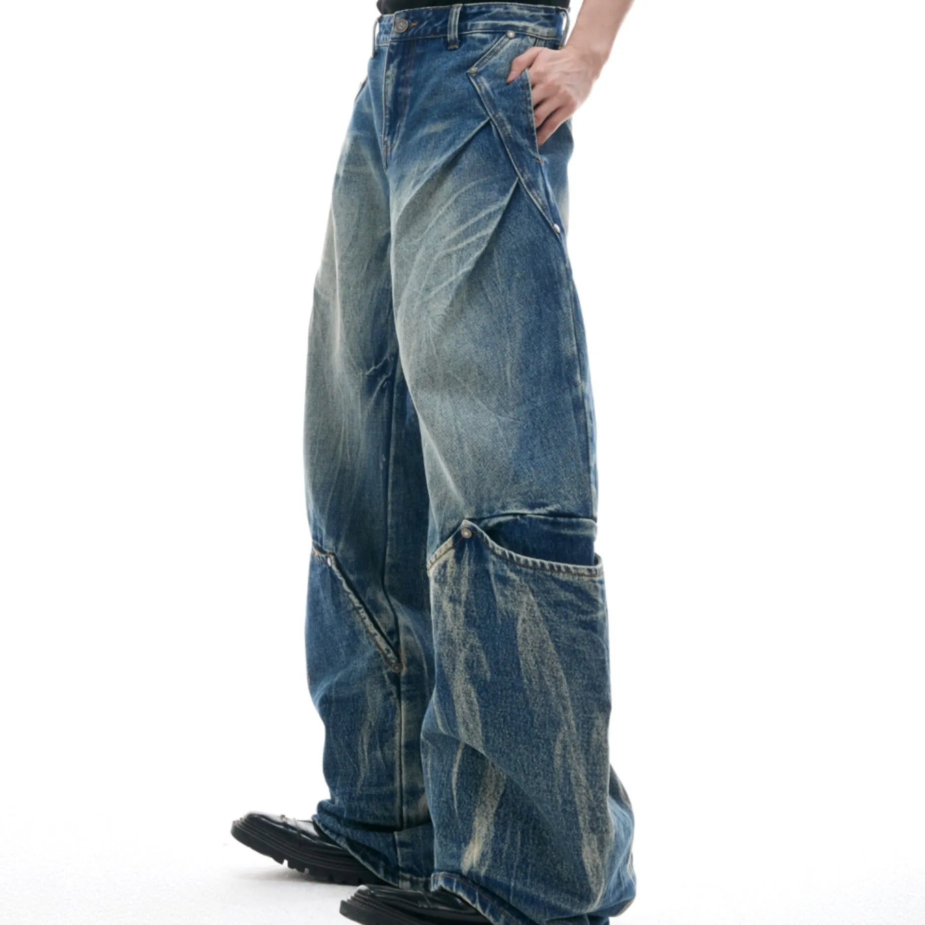 Men's verdant blue jeans with washed burst pattern and curved knife design, showing loose fit and retro style.