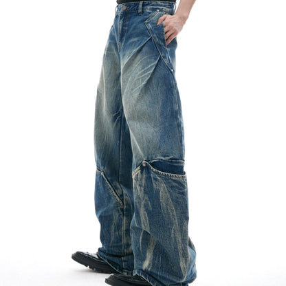 Men's verdant blue jeans with washed burst pattern and curved knife design, showing loose fit and retro style.