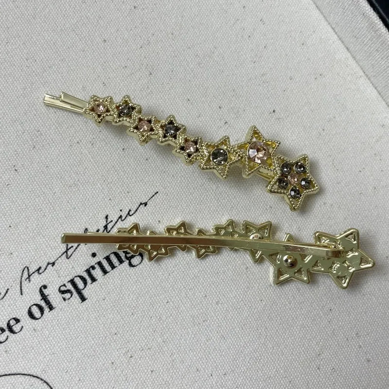 Gold electroplated hair barrette with a rhinestone five-pointed star, broken clip style for bangs.
