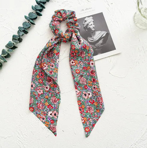 Spring dark green cloth ribbon hair tie tied in a large knot, showing seiko-treated fabric and floral detail.
