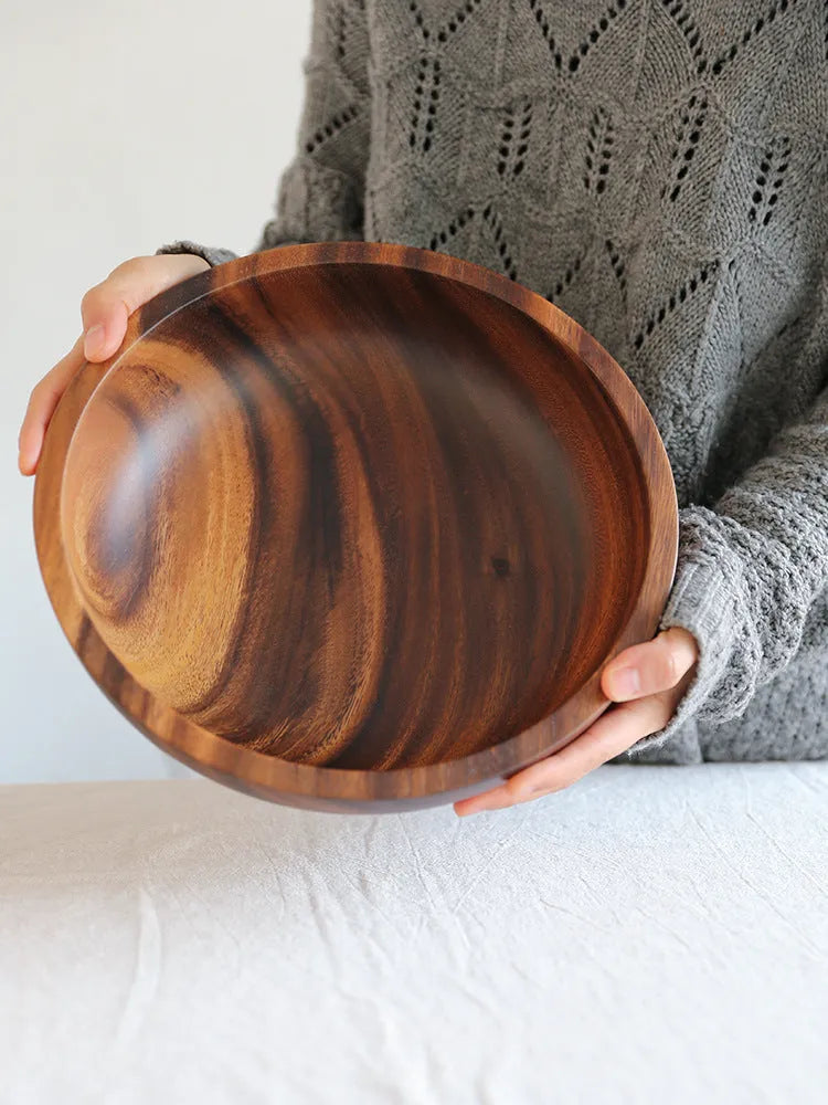 Brown handmade wooden serving bowl with natural wood grain on a table.