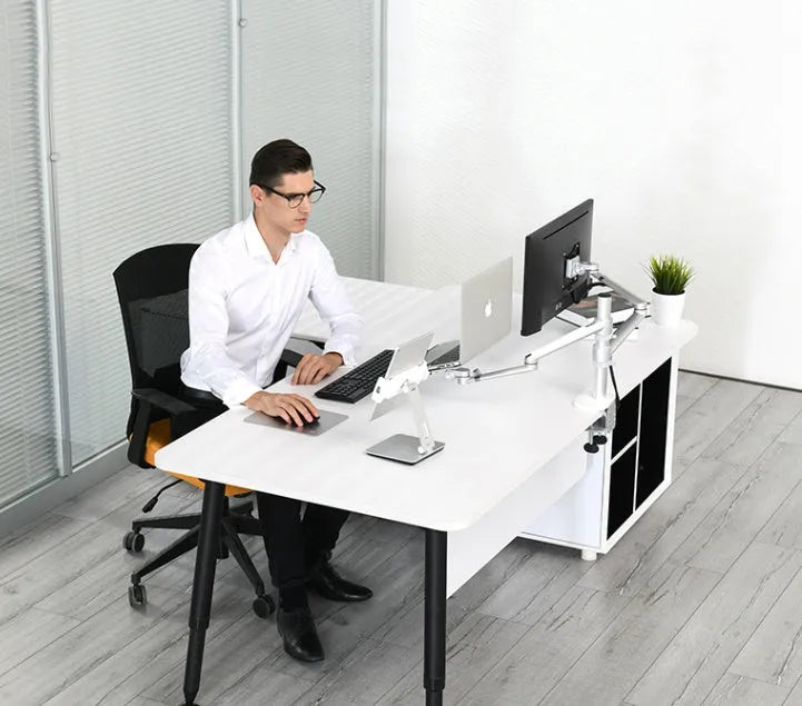 Silver foldable aluminium phone and tablet holder on a wooden desk, showing 360-degree rotation and silicone pads.
