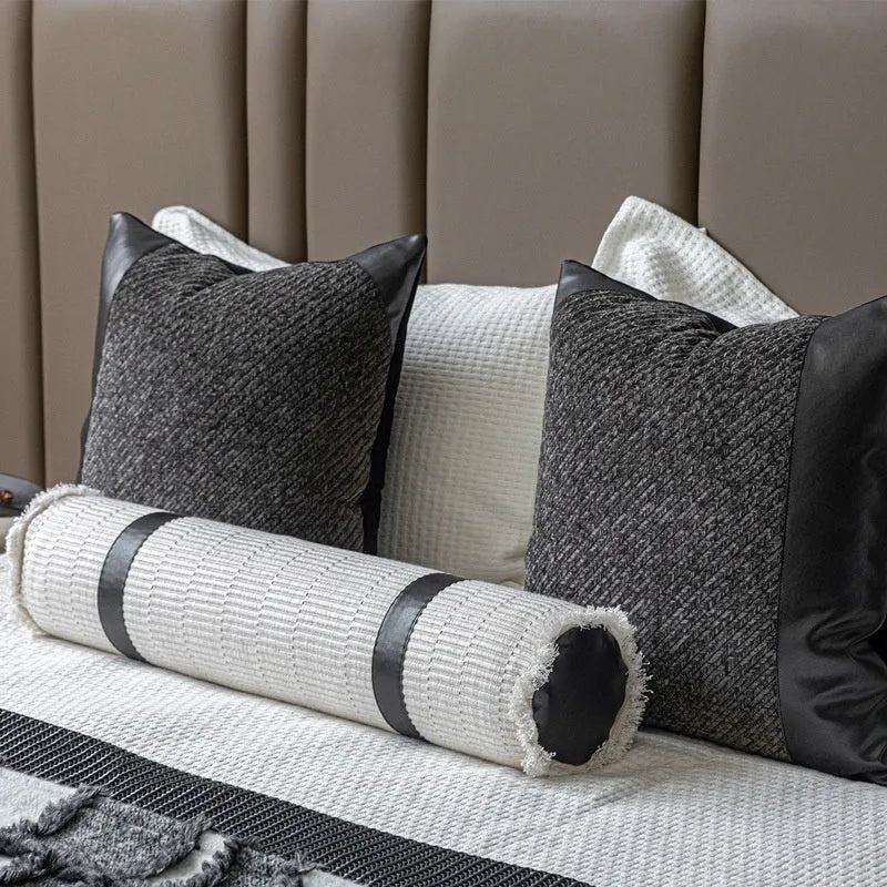 Grey and white plaid bed runner blanket with coordinating pillowcase and round leather pillow on bed
