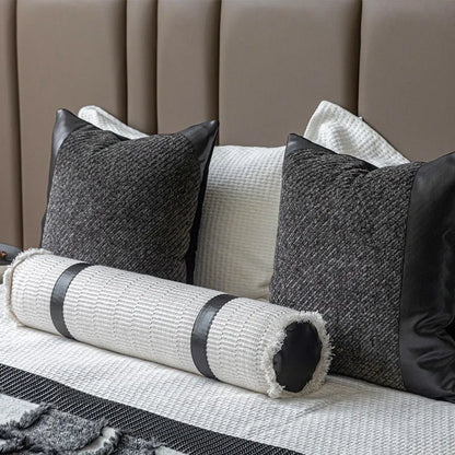 Grey and white plaid bed runner blanket with coordinating pillowcase and round leather pillow on bed