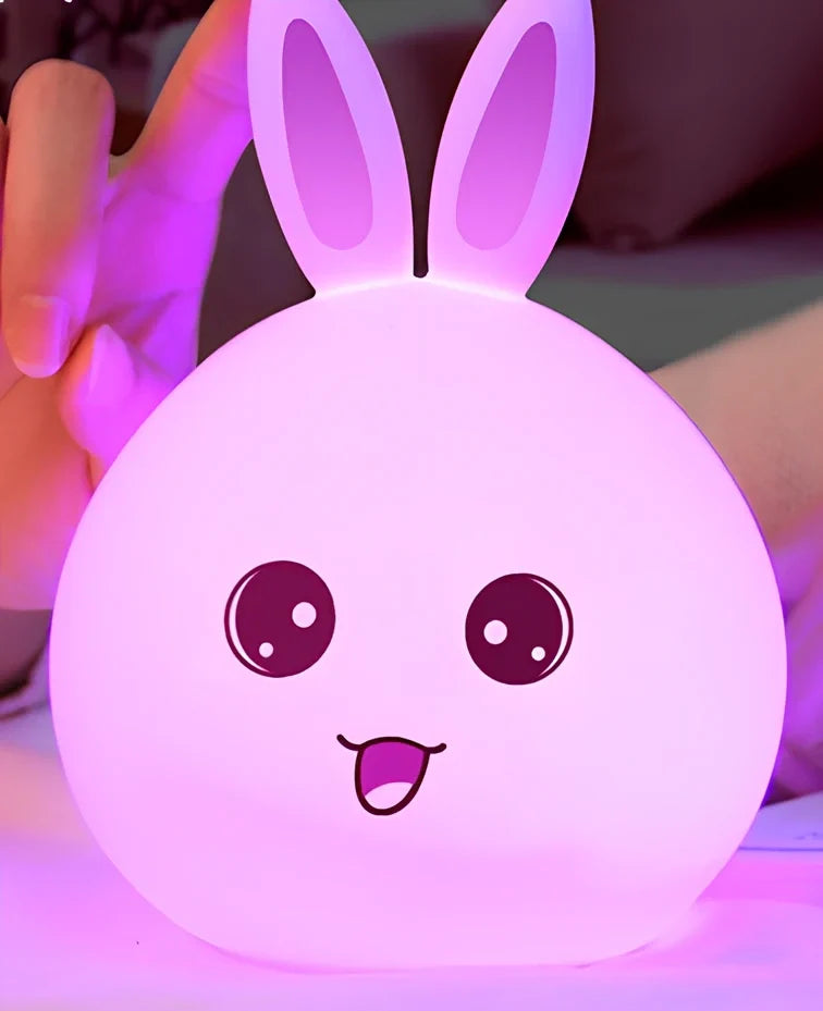 White silicone rabbit night light with USB charging cable showing touch sensor area and colourful LED illumination