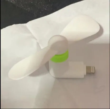 White portable mobile phone mini fan with plastic blades attached to smartphone
