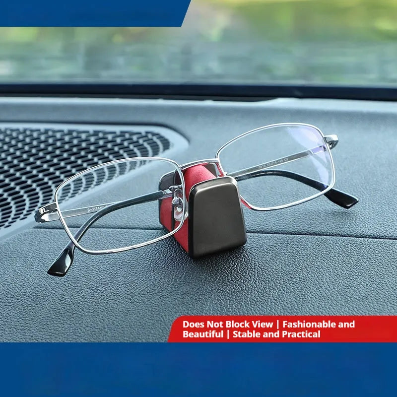Green zinc alloy and leather glasses clip holder attached to a car dashboard, holding sunglasses.