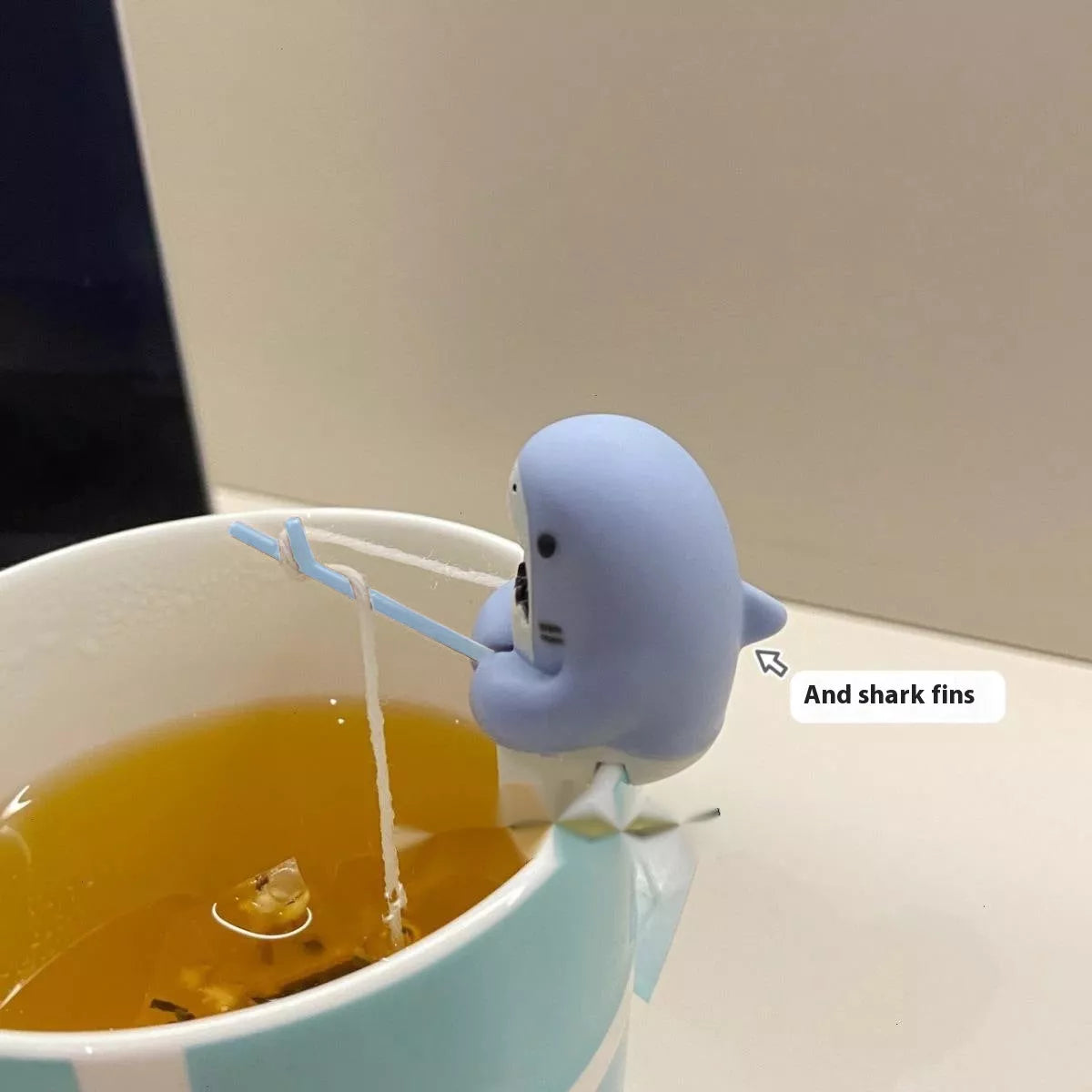 Shark-shaped tea infuser hanging on cup edge, made from food-grade silicone