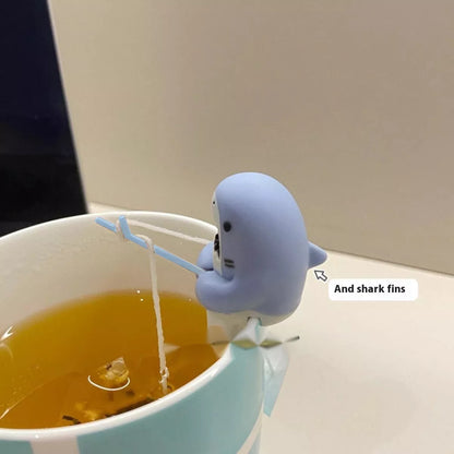 Shark-shaped tea infuser hanging on cup edge, made from food-grade silicone