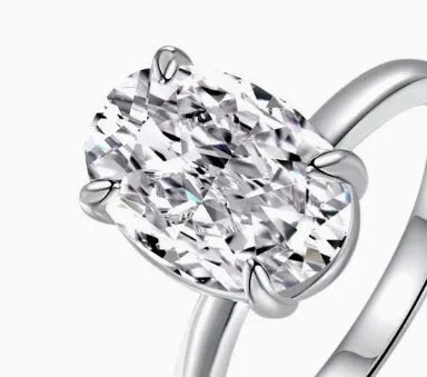 Oval silver ring with four-prong setting and a hand-cut stone on a finger.