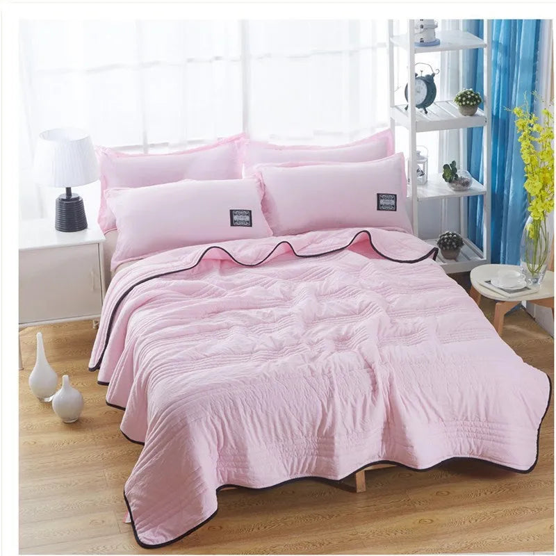 Lightweight plain coloured polyester summer quilt on a bed