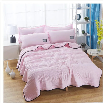 Lightweight plain coloured polyester summer quilt on a bed