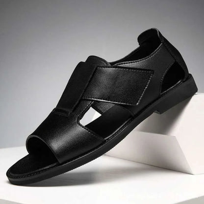 Men's brown leather Roman-style sandals with an open toe and a textured rubber sole on a wooden surface.