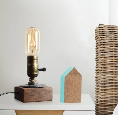 Compact wooden and iron water pipe table lamp on a table.