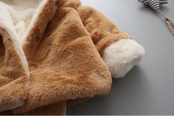 Baby wearing pink cotton coat with velvet accents, showing flocking fabric texture and cotton filling insulation