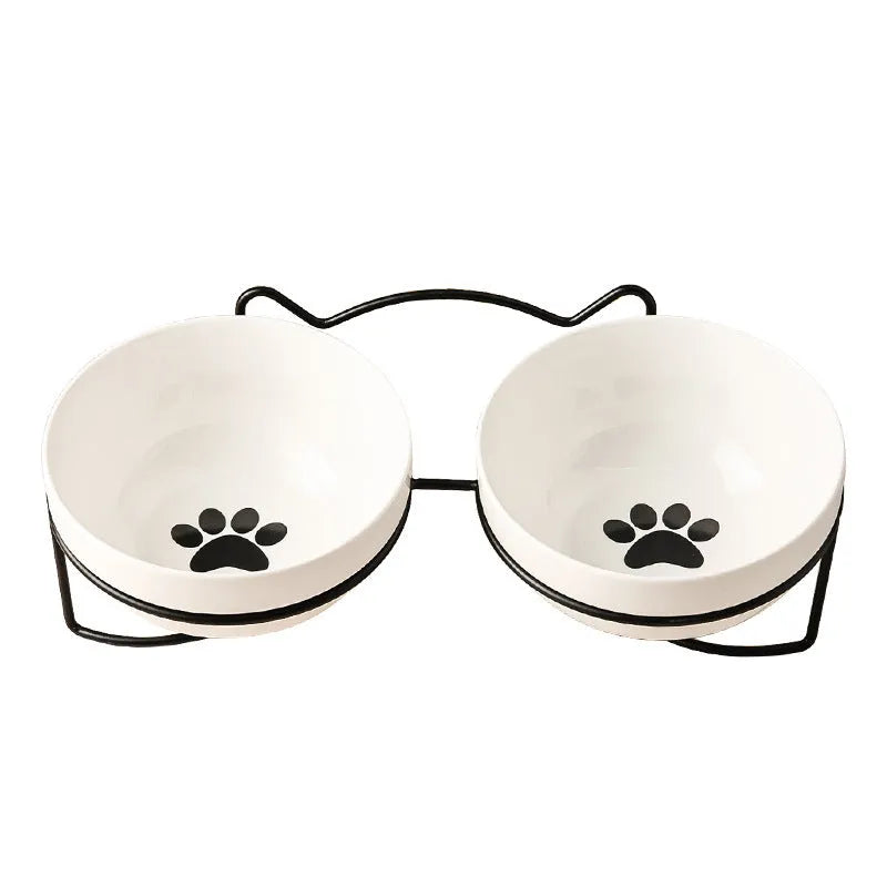 White ceramic pet bowl with cat paw design on a black iron frame raised feeder.