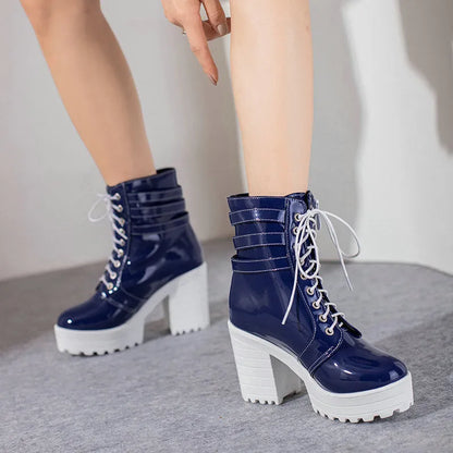Women's black lace-up ankle boots with a round toe and thick 6-8cm platform heel on a wooden floor.