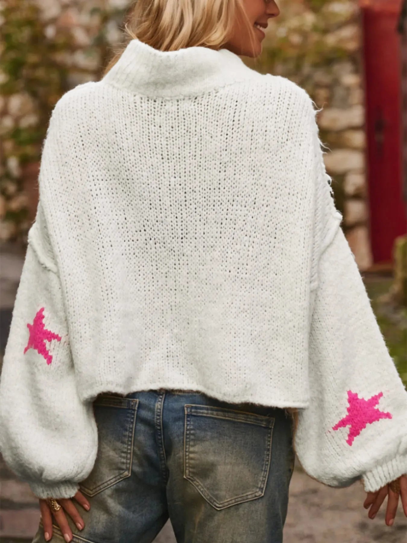 White women's turtleneck pullover with a black star pattern, loose fit, and long sleeves.